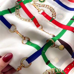 Macro detail of silk-like scarf featuring vintage chain and leather strap patterns