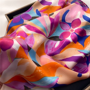 Detalle de una bufanda de seda suave con vibrantes motivos florales abstractos en violeta