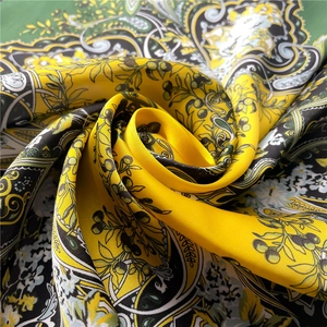Detail of silk-like paisley square scarf showing rich yellow-green print and glossy texture