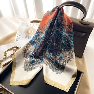 Retro paisley print silk scarf in orange and blue tied on a leather handbag