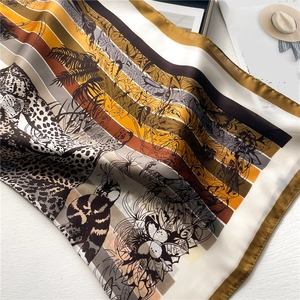 Close-up of leopard and tropical leaf patterns on a colorful striped silk scarf