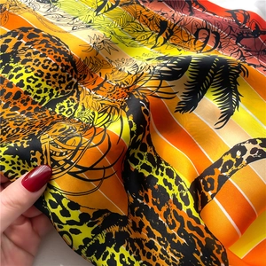 Detailed close-up of leopard and palm leaf print scarf with silky texture and vibrant stripes
