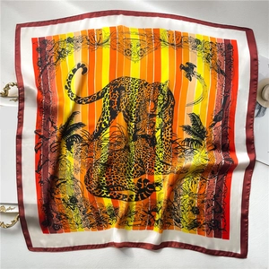 Detail of square silk scarf showing tropical leopard and floral print with striped background