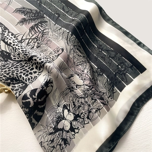 Detailed close-up of silk scarf featuring leopard, tropical birds and leaf patterns