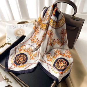 Baroque pattern silk scarf in beige and navy blue draped on a leather handbag