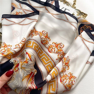Close-up of silk-textured scarf featuring baroque gold chain and lion head patterns