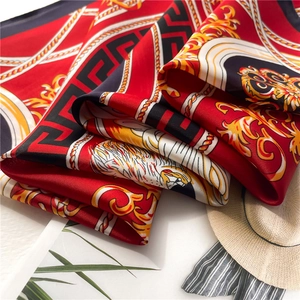 Close-up of red silk scarf with golden Baroque prints and white tiger head detail