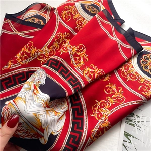 Detailed shot of red silk scarf with golden Baroque lion patterns and Greek key borders