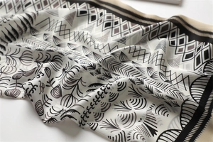 Detailed view of black and white silk-like square scarf with geometric and floral prints