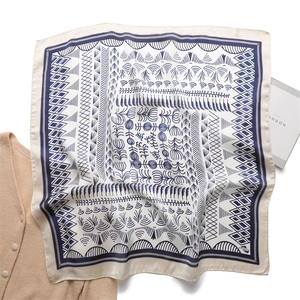 Detail of silk square scarf with navy geometric patterns on beige fabric background