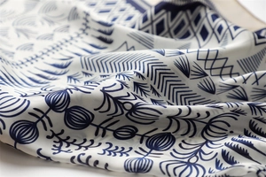 Macro shot of smooth silk texture with navy blue geometric floral print on cream fabric