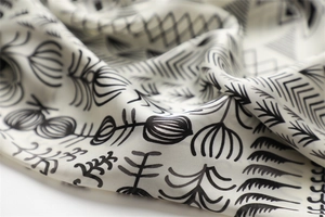 Detail shot of ivory silk square scarf featuring black abstract geometric plant patterns