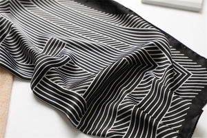 Detail of silk-like scarf featuring black and white geometric stripes and smooth texture