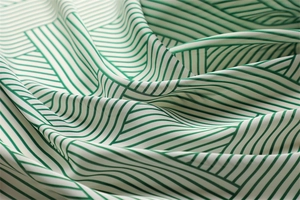 Detail of striped silk square scarf showing forest green geometric patterns and silky texture