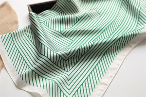 Detail of green and white geometric stripe silk scarf with glossy texture and smooth drape