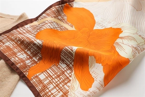 Detail of silk square scarf featuring bright orange lilies and brown checkered patterns