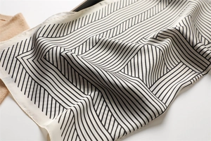 Detailed view of striped silk scarf with elegant black geometric diagonal lines on ivory