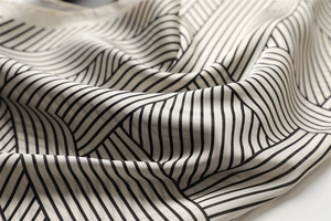 Close-up of black and white striped silk scarf showing soft fabric texture and satin sheen
