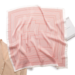 Chic orange striped square silk scarf laid on a white surface with lifestyle props