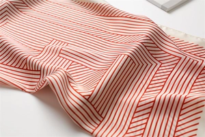 Close-up of red and white geometric striped silk scarf showing soft fabric texture