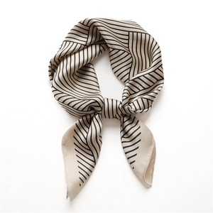 Close-up of silk-like square scarf with elegant black geometric stripes on beige base