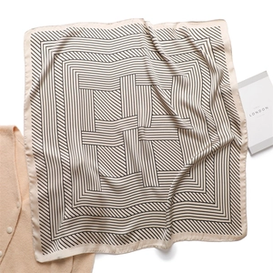 Close-up of elegant beige striped silk square scarf with geometric pattern detail