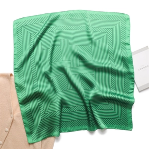 Macro detail of glossy emerald silk scarf with black geometric labyrinth stripe patterns