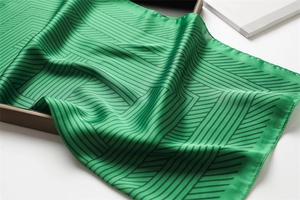 Detailed view of luxury green silk square scarf with geometric black stripes texture