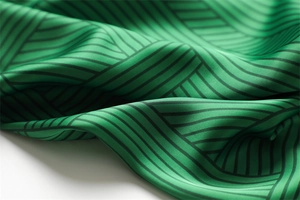 Detail of silk satin fabric with green and black geometric stripes showing smooth texture