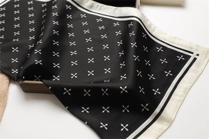 Détail du foulard en soie montrant un imprimé géométrique et une texture de satin lisse