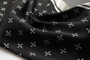 Détail d'un foulard en satin de soie avec motifs géométriques et bordure rayée