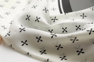 Détail d'un foulard en soie avec motifs de croix noires et texture lisse et brillante