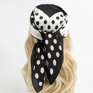 Chic black and white polka dot silk scarf tied as a hair accessory on model