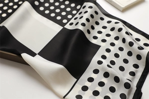 Detailed view of black and white polka dot silk scarf texture and modern geometric pattern