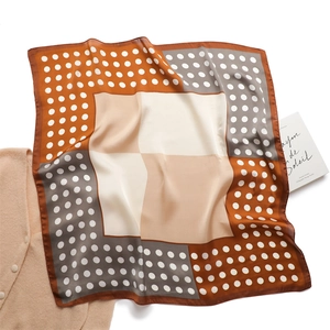 Elegant polka dot and block pattern square silk scarf displayed on a white cardigan