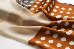 Detail of silk-like scarf with orange-brown polka dot pattern and satin texture