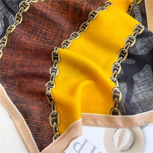 Dettaglio di sciarpa in seta con motivi a catena dorata e design patchwork colorato