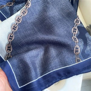 Dettaglio di sciarpa in seta blu scuro con stampe a catena e finitura trasparente