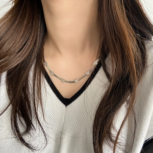 Close-up of minimalist silver snake chain necklace with five mini heart pendants on neck