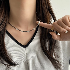 Detail view of silver heart choker necklace with snake chain on model's neckline