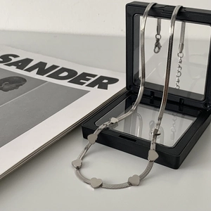 Minimalist silver snake chain necklace with multiple heart pendants on a display stand