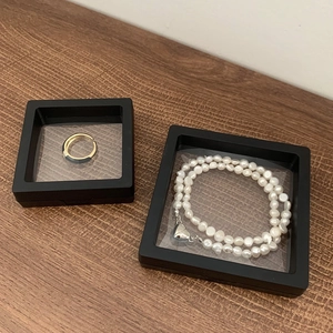 Suspended jewelry display box with black gold ring and heart clasp pearl necklace