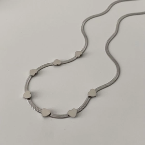 Detail of silver flat snake chain necklace with multiple polished heart-shaped pendants