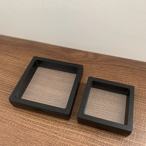 Detail of black PE film floating jewelry box with push-to-open latch on wooden surface