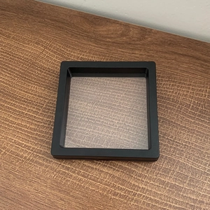 Square black jewelry display box with clear PE film on brown wood background