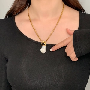 Gros plan d'un collier Figaro doré avec une perle baroque et un fermoir à bascule type OT