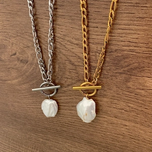 Colliers en perles baroques avec fermoir OT en or et argent sur fond bois de noyer