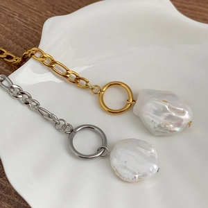 Détail de colliers en perles baroques avec fermoirs OT en or et argent sur plateau coquille