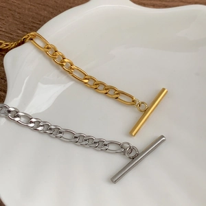 Détail des bracelets Figaro or et argent avec fermoir à bascule sur un plateau en coquillage