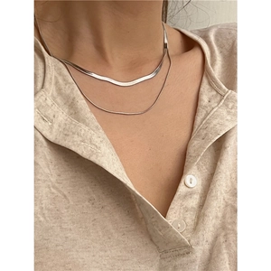Minimalist double layer silver snake chain necklace on model with light beige shirt